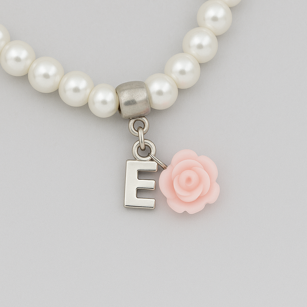 Pearl bracelet with a silver 'E' charm and pink rose on a light gray background