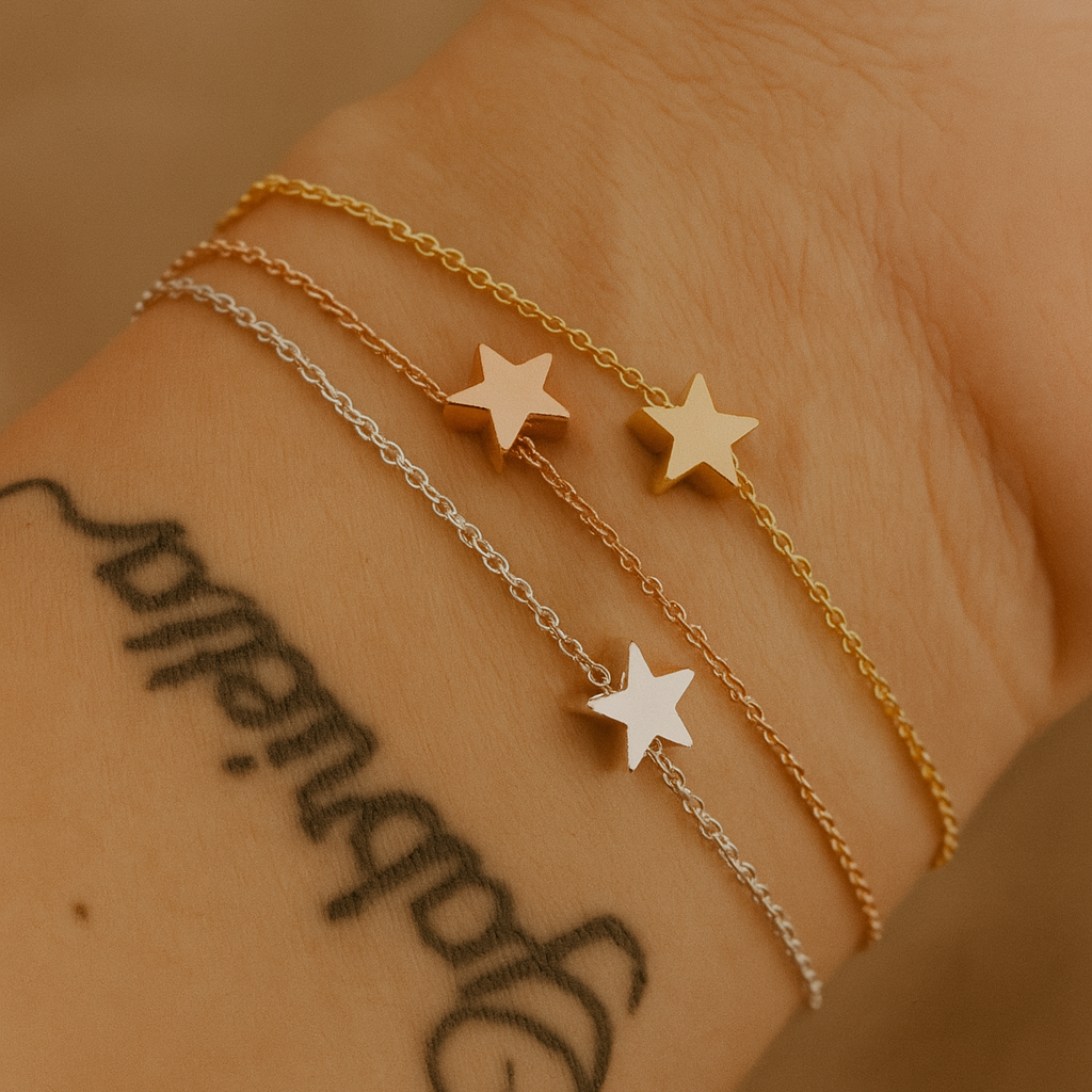 Three bracelets in rose gold silver and gold with a star on each bracelet on a wrist with visible tattoos 