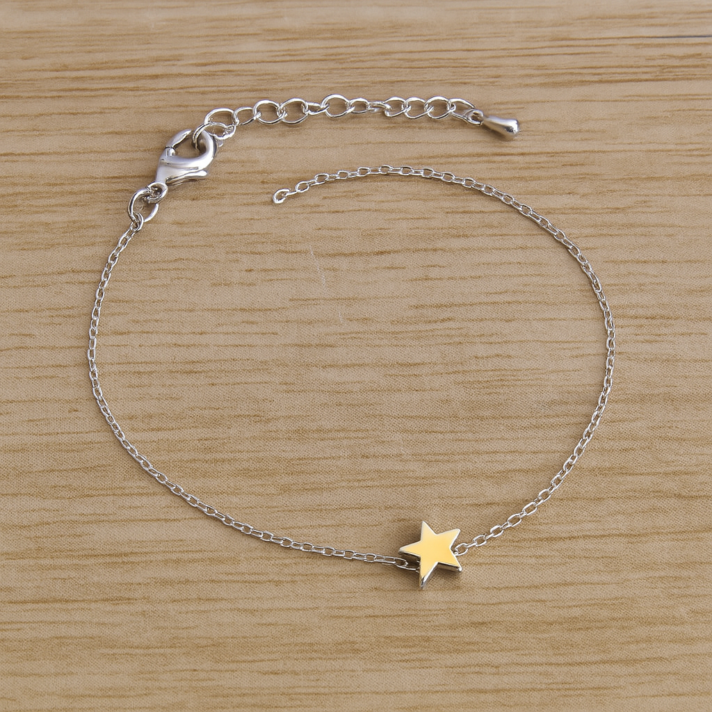 Silver bracelet with a silver star charm on a wooden surface