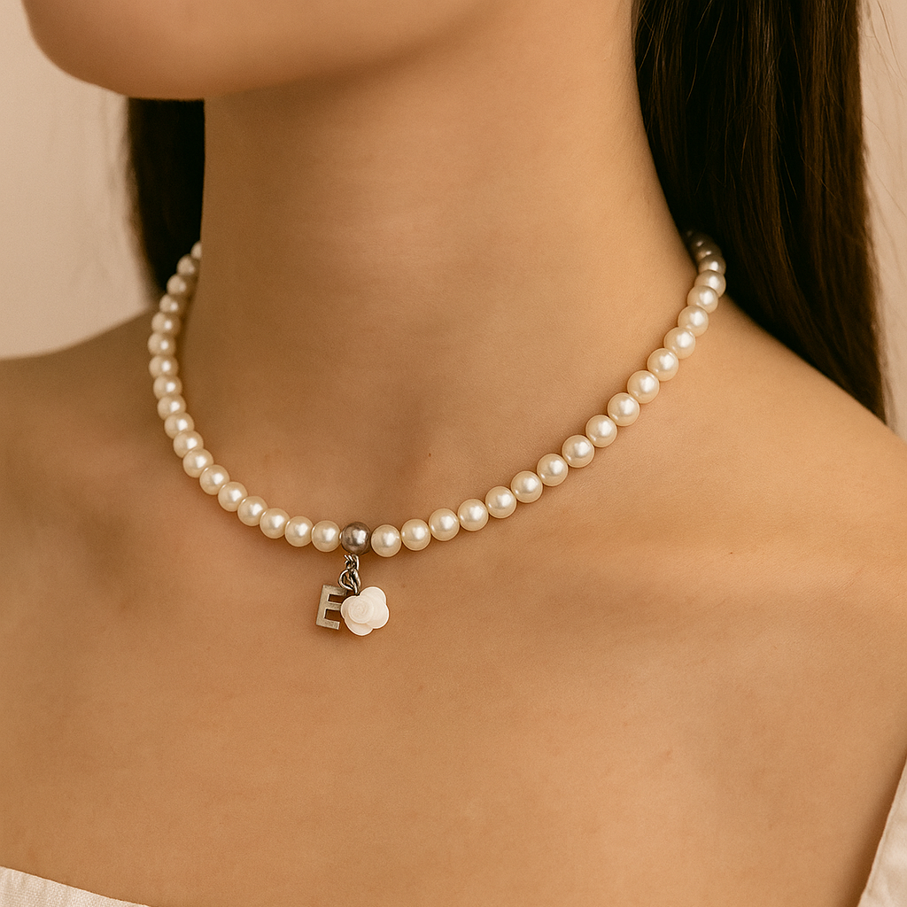 Pearl necklace with a flower charm worn by a person against a neutral background