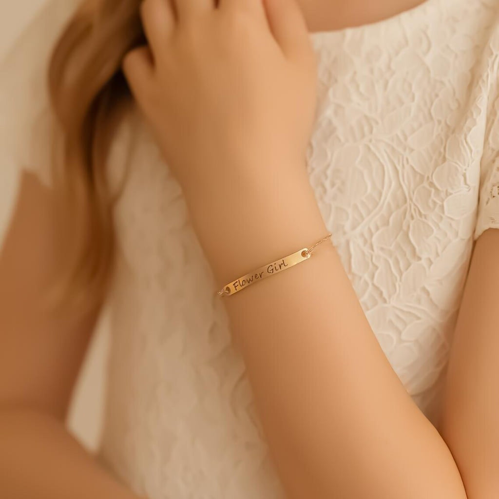 Gold bracelet with engraved text on a person's wrist against a neutral background