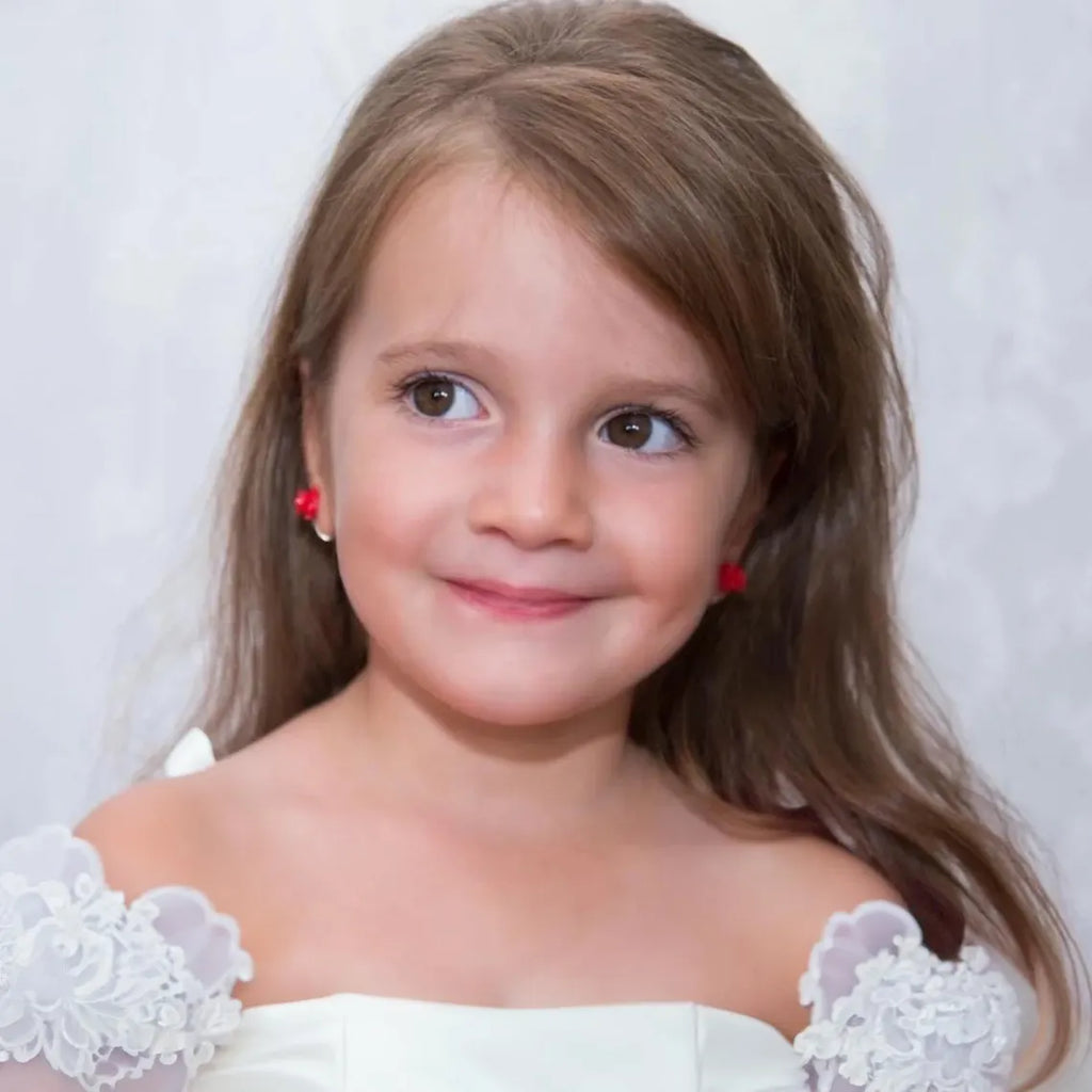 Young girl with long brown hair wearing a white dress against a light background